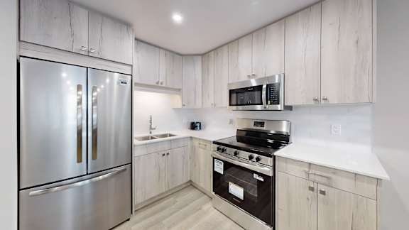 A kitchen with a stainless steel refrigerator and a microwave above the stove.