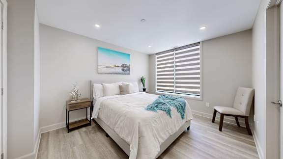 A bedroom with a bed, a chair, and a painting on the wall.