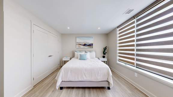 A bedroom with a large bed and a picture on the wall.