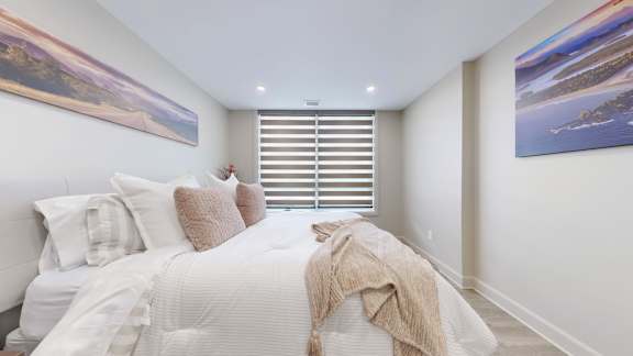 A bedroom with a large bed and two pictures on the wall.