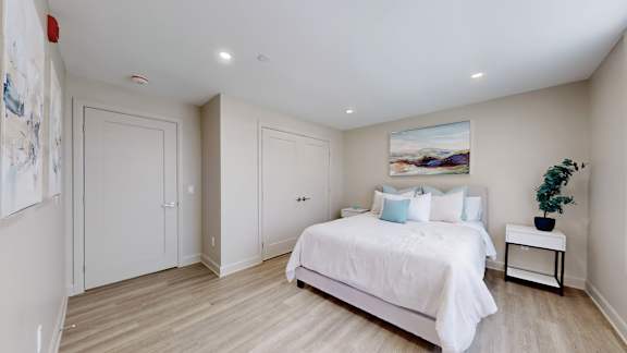 A bedroom with a large bed and a painting on the wall.