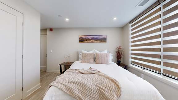 A bedroom with a large bed and a painting on the wall.