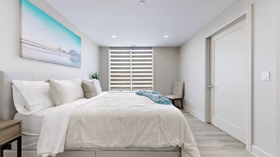 A bedroom with a large bed and a painting on the wall.