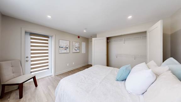 A bedroom with a white bed and a chair.