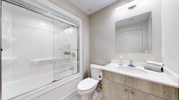 A white bathroom with a toilet, sink, and shower.