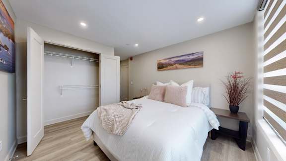 A bedroom with a large bed and a painting on the wall.