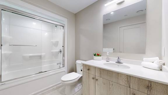 A white bathroom with a toilet, sink, and shower.