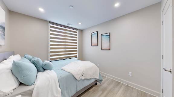 A bedroom with a bed, pillows, and two pictures on the wall.