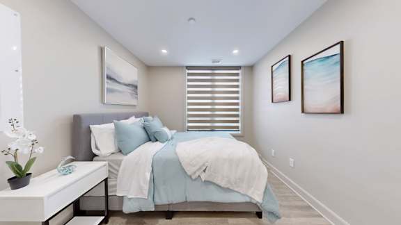 A bedroom with a bed, a bench, and two pictures on the wall.