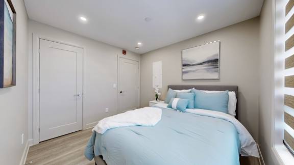 A bedroom with a bed, nightstand, and two doors.