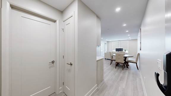 A white hallway with a dining table and chairs in the background.