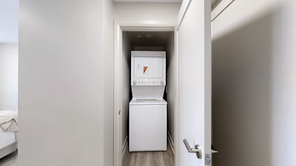 A white washing machine is in a small white room.