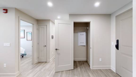 A hallway with white walls and wood flooring with a person in the background.