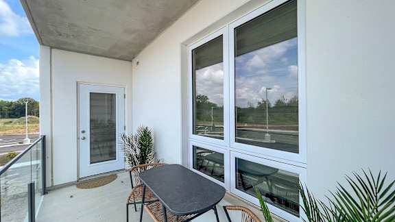 A balcony with a table and chairs overlooking a parking lot.