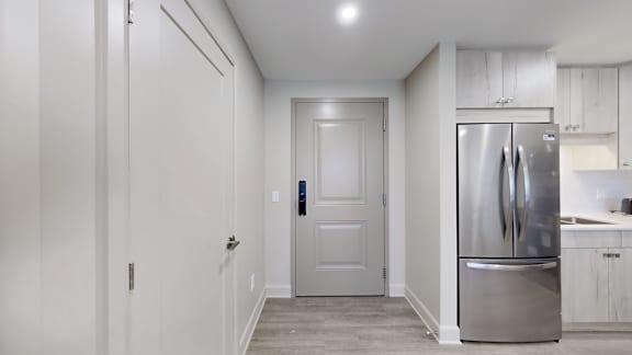 A kitchen with a refrigerator, sink, and cabinets.