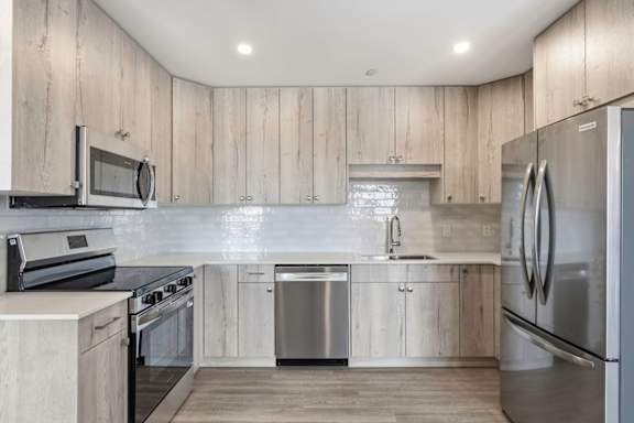 A modern kitchen with wooden cabinets and stainless steel appliances.