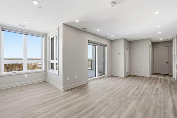 A spacious room with wooden flooring and large windows.