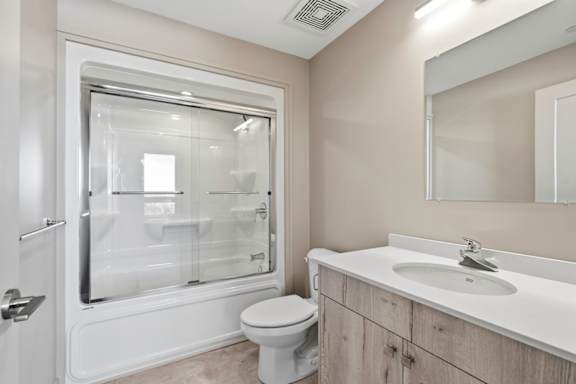 A bathroom with a toilet, sink, and a glass shower door.