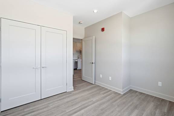 A room with white doors and a red fire alarm.