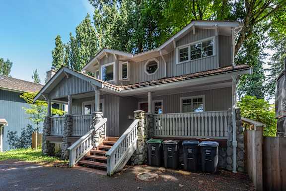 A house with a grey roof and a balcony surrounded by trees.