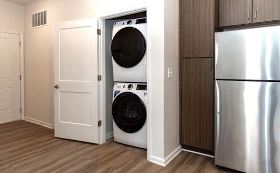 A white door is open to reveal a black washing machine inside.
