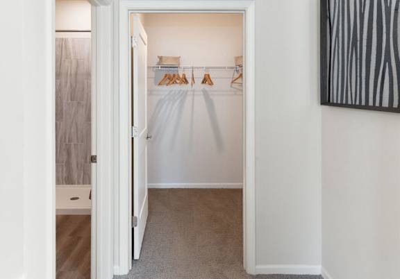 A white closet with clothes hanging on a rack.
