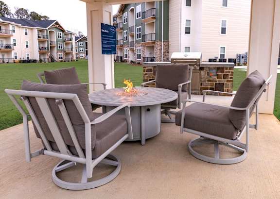 A patio table with chairs and a fire pit in the middle.