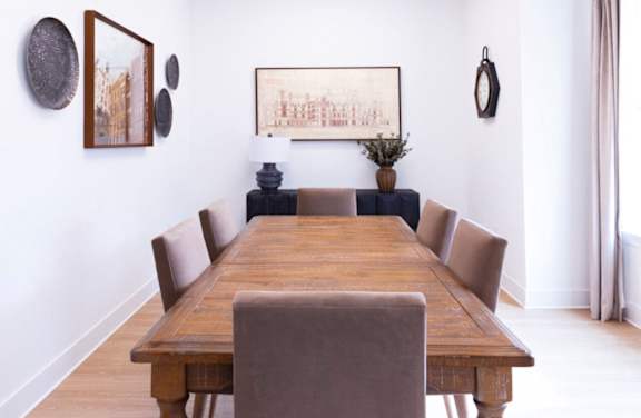 A long wooden table with chairs and pictures on the wall.