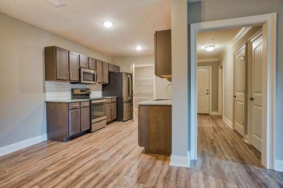 A kitchen with brown cabinets and a wooden floor at Mode at Melbourne, LLC Apartments, Florida, 32901