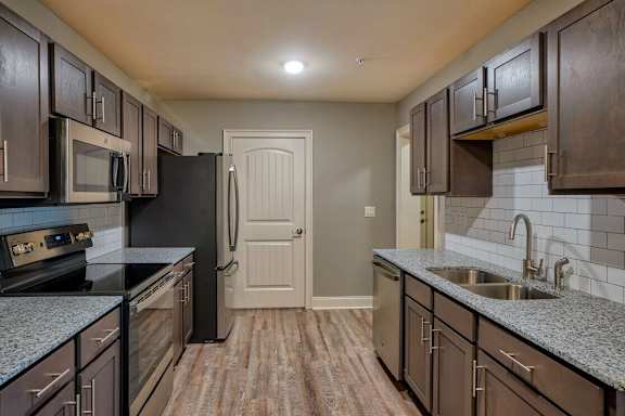 A kitchen with dark brown cabinets and a black refrigerator at Mode at Melbourne, LLC Apartments, Florida, 32901