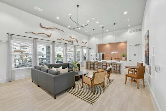 A living room with a grey couch, wooden chairs, and a rug.at Allegra at Cocoa in Cocoa, FL, 32926