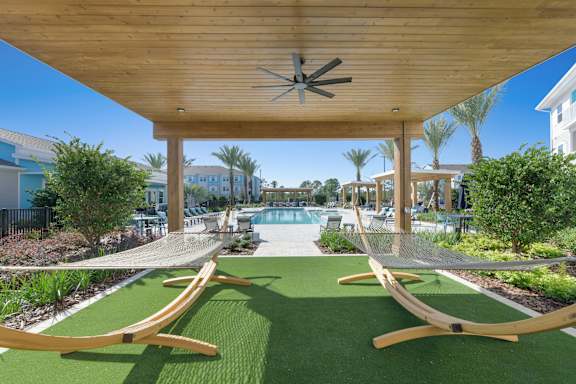 A wooden pergola with a ceiling fan is over a green lawn with two hammocks.at Allegra at Cocoa in Cocoa, FL, 32926