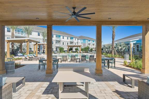A patio with a table and chairs under a roof.at Allegra at Cocoa in Cocoa, FL, 32926