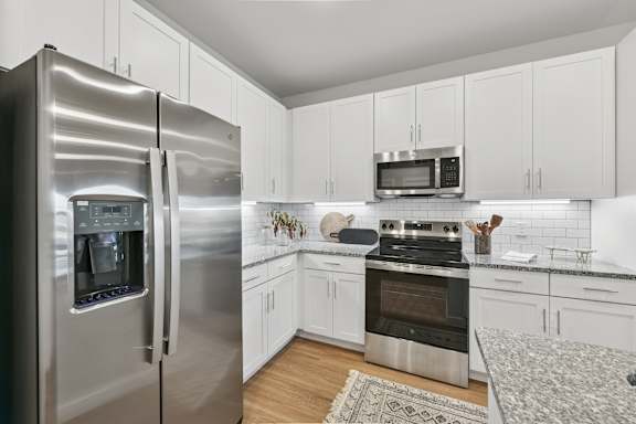 A modern kitchen with a stainless steel refrigerator and white cabinets.at Allegra at Cocoa in Cocoa, FL, 32926