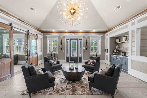A living room with a large chandelier and a rug at Mode at Melbourne, LLC Apartments, Florida, 32901