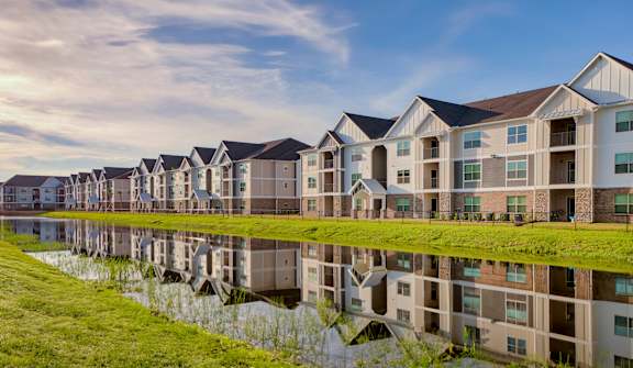 A row of modern houses are reflected in the water in front of them at Mode at Melbourne, LLC Apartments, Florida, 32901