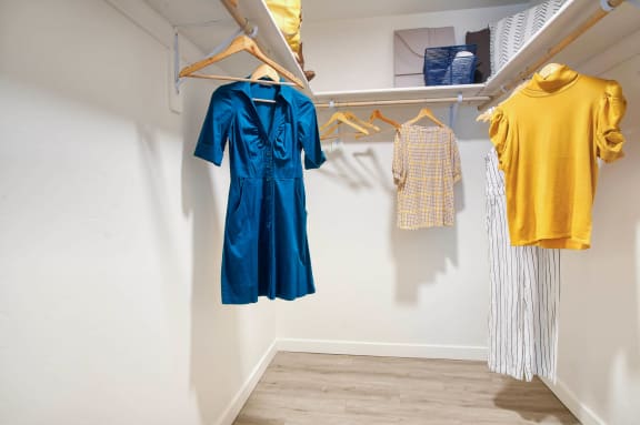 a room with clothes hanging on a rack and a closet at Presidio Palms Apartments, Tucson, AZ