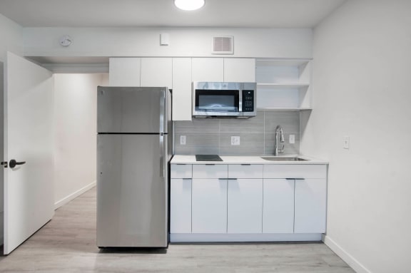 a kitchen with white cabinets and a stainless steel refrigerator at Presidio Palms Apartments, Tucson, Arizona