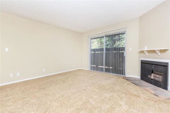 an empty living room with a fireplace and a window
