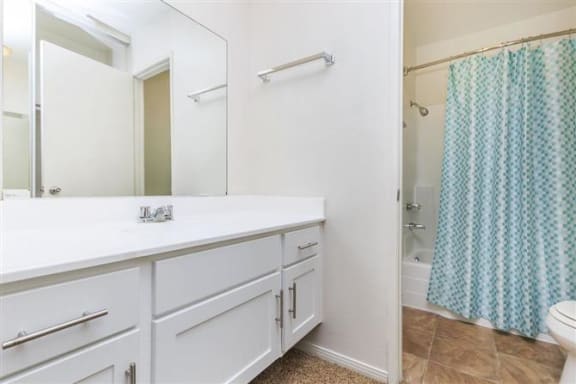 a bathroom with a white counter top and a blue shower curtain