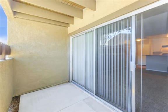 a patio with a sliding glass door and a kitchen in the background