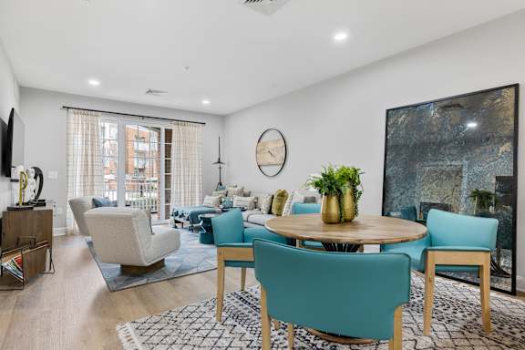 A living room with a large painting on the wall and a dining table with chairs around it.