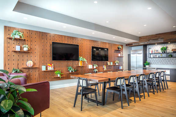 Communal dining room with long wooden table and pegboard wall at Inwood at Renaissance Square Apartments, Marlton, NJ 08053