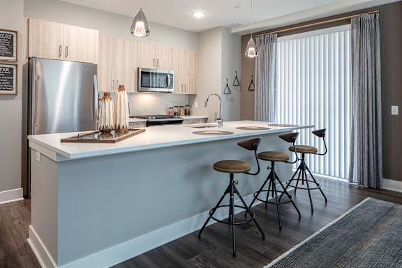 Kitchen island with bar seating and pendant lights at Inwood at Renaissance Square Apartments, Marlton