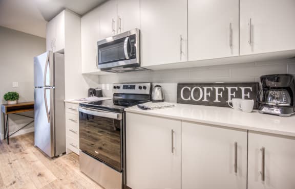 a kitchen with white cabinets and appliances and a coffee sign