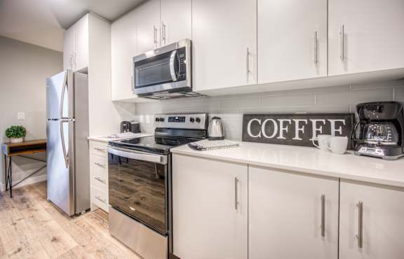 A modern kitchen with a refrigerator, stove, and microwave.