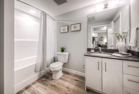 A white toilet sits in a bathroom with a white shower curtain.