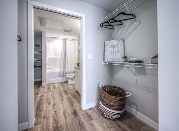 A white room with a wooden floor and a white door leading to a bathroom.