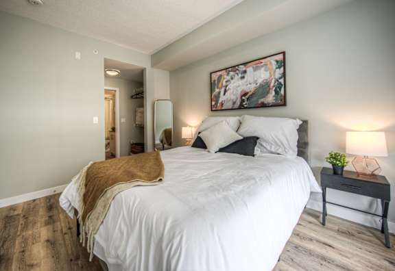 A bedroom with a large bed and a painting on the wall.