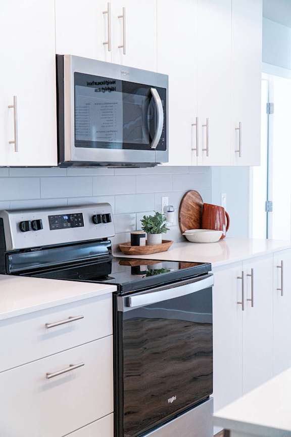 A modern kitchen with a black oven and white cabinets.